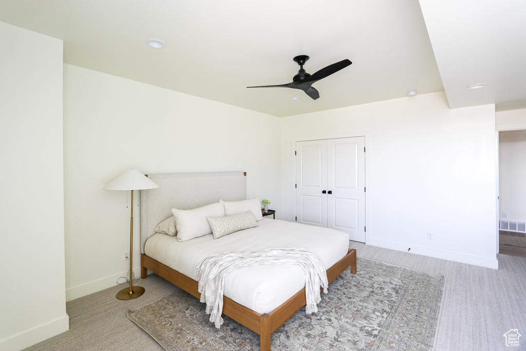 Bedroom with a closet, ceiling fan, and light colored carpet