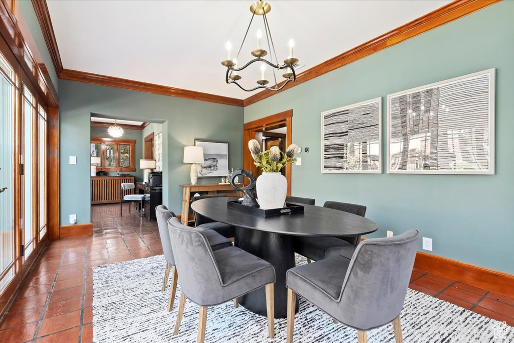 Tiled dining area featuring a chandelier and crown molding