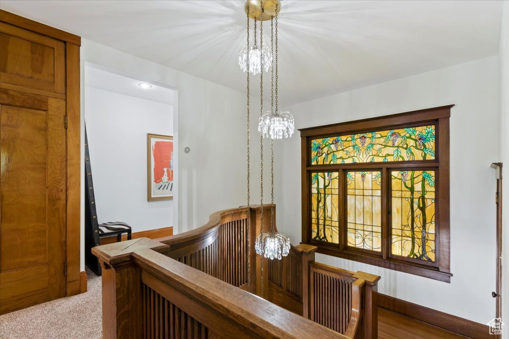 Hall featuring carpet flooring and an inviting chandelier