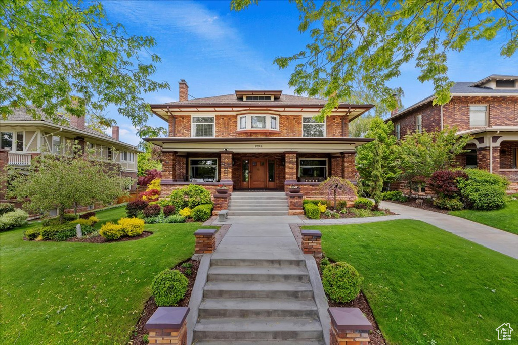 View of front of home featuring covered porch and a front lawn