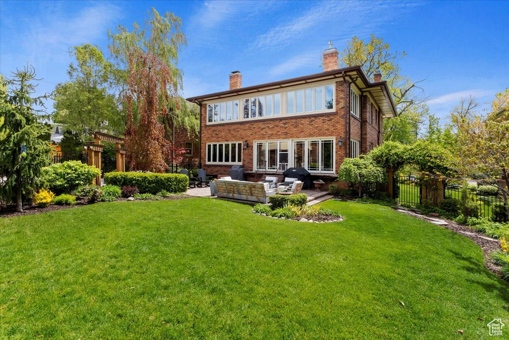 Rear view of property featuring an outdoor hangout area, a lawn, and a patio