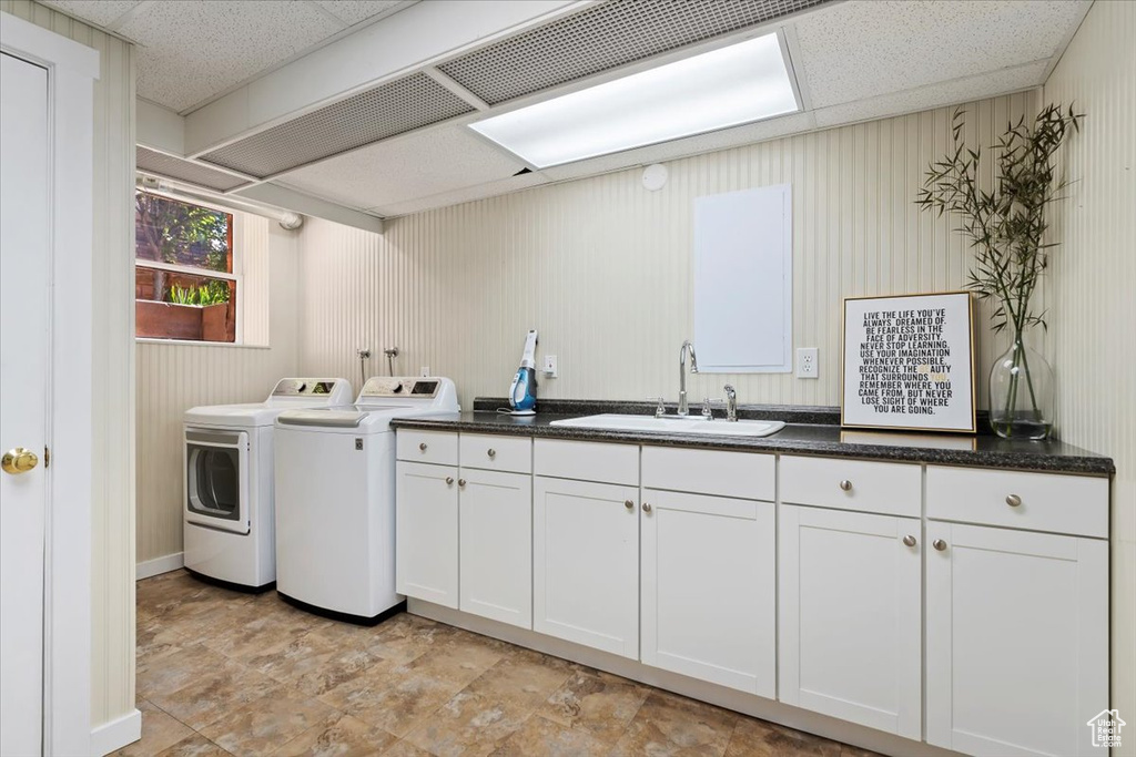 Clothes washing area with cabinets, sink, and independent washer and dryer