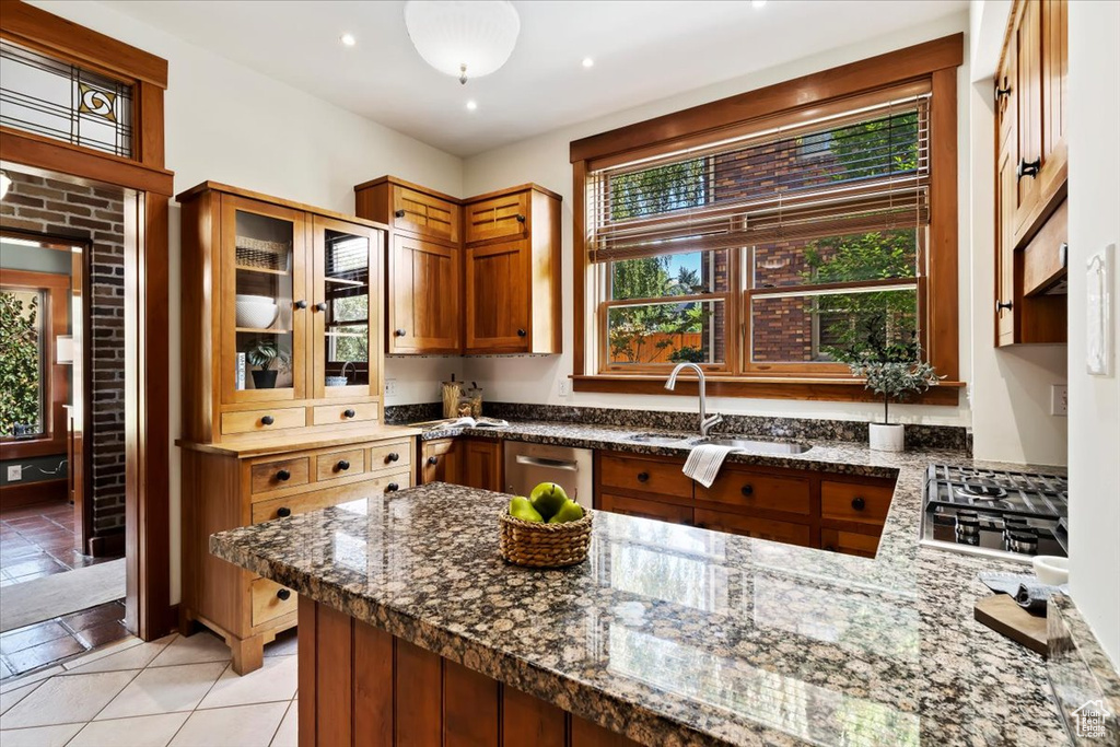 Kitchen featuring dark stone countertops, sink, stainless steel appliances, and kitchen peninsula