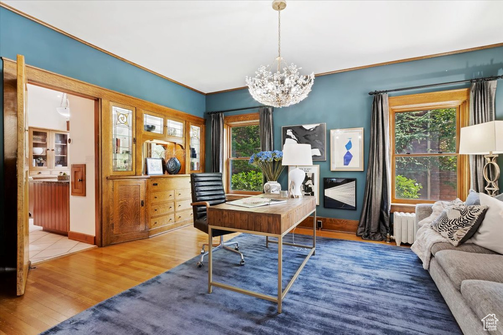 Office space with light wood-type flooring, radiator, a notable chandelier, and ornamental molding