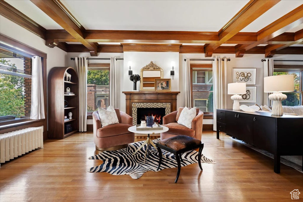 Living area featuring light wood-type flooring, coffered ceiling, a fireplace, and radiator