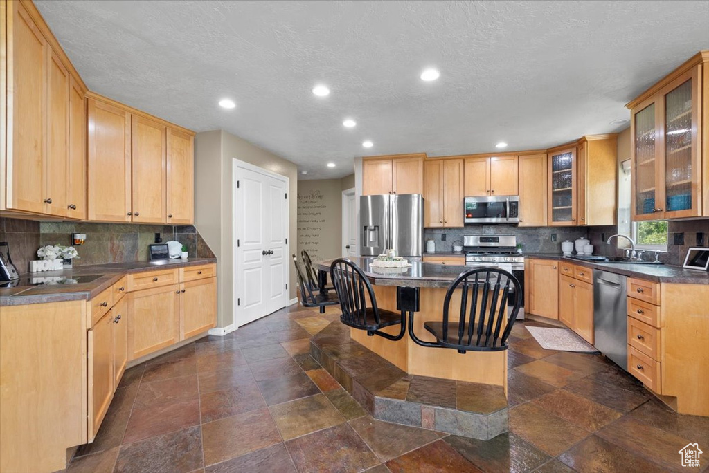 Kitchen featuring tasteful backsplash, a kitchen bar, a kitchen island, and stainless steel appliances