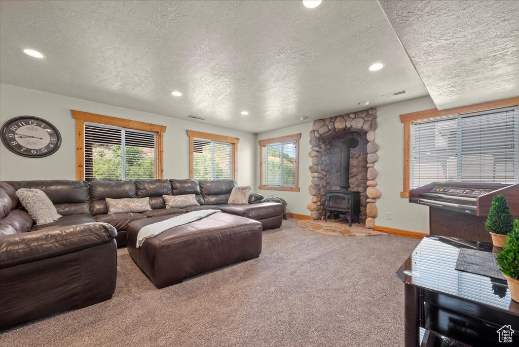 Carpeted living room with a textured ceiling and a wood stove