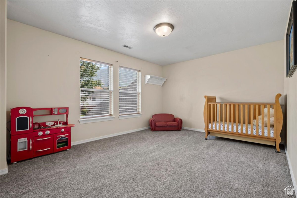 Carpeted bedroom featuring a crib