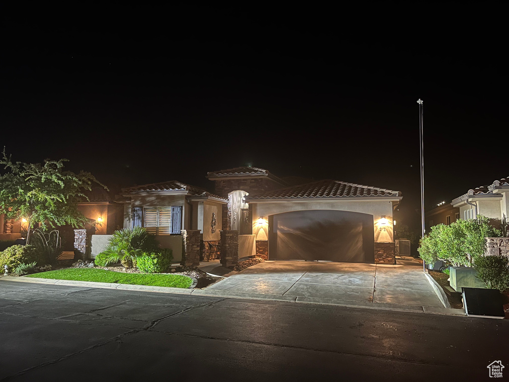 View of front of house with an attached garage, stucco siding, driveway, and a tile roof
