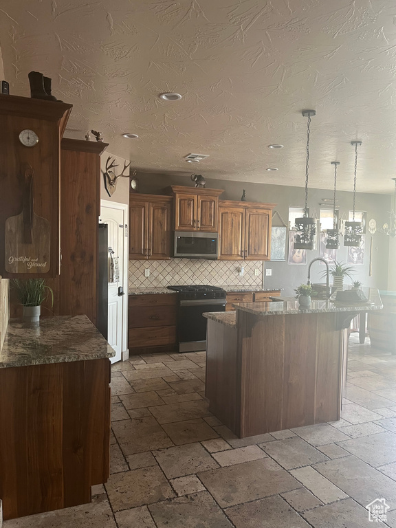 Kitchen featuring dark stone counters, tasteful backsplash, appliances with stainless steel finishes, and stone tile flooring