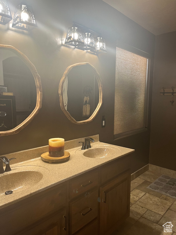 Bathroom with stone tile flooring, a sink, and double vanity