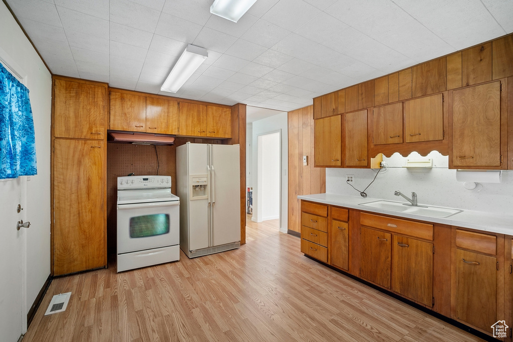 Kitchen with sink, light hardwood / wood-style flooring, and white appliances