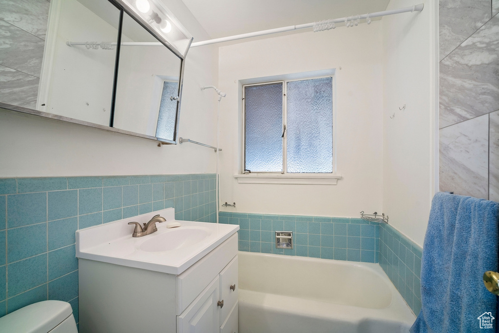 Bathroom featuring tile walls, toilet, and vanity