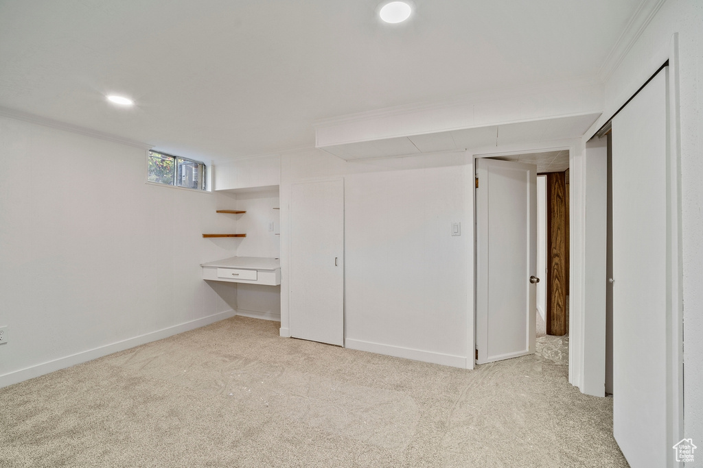 Unfurnished bedroom featuring light colored carpet, a closet, and ornamental molding