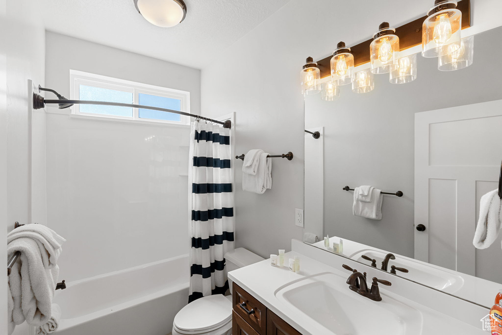 Full bathroom featuring vanity, toilet, and shower / bath combination with curtain