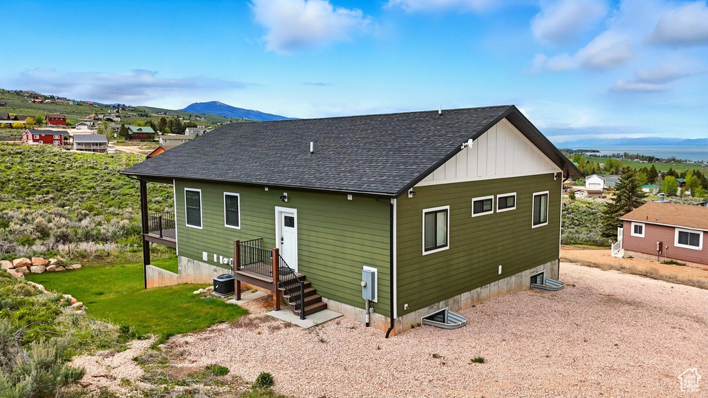 Rear view of house with roof with shingles, a mountain view, and central air condition unit