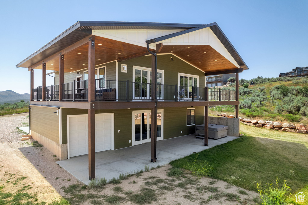 Rear view of house featuring a garage, a balcony, a patio, and french doors