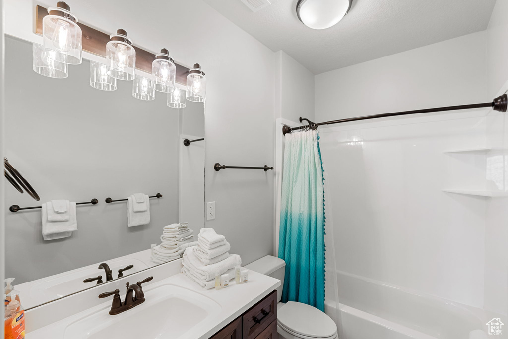 Full bathroom featuring shower / bathtub combination with curtain, toilet, and vanity