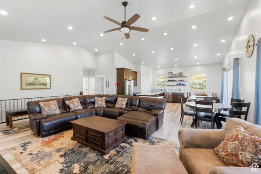 Living room with high vaulted ceiling, light wood-type flooring, and ceiling fan