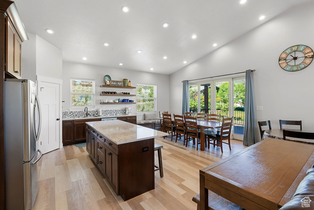 Kitchen featuring decorative backsplash, a center island, stainless steel refrigerator, and light wood-type flooring