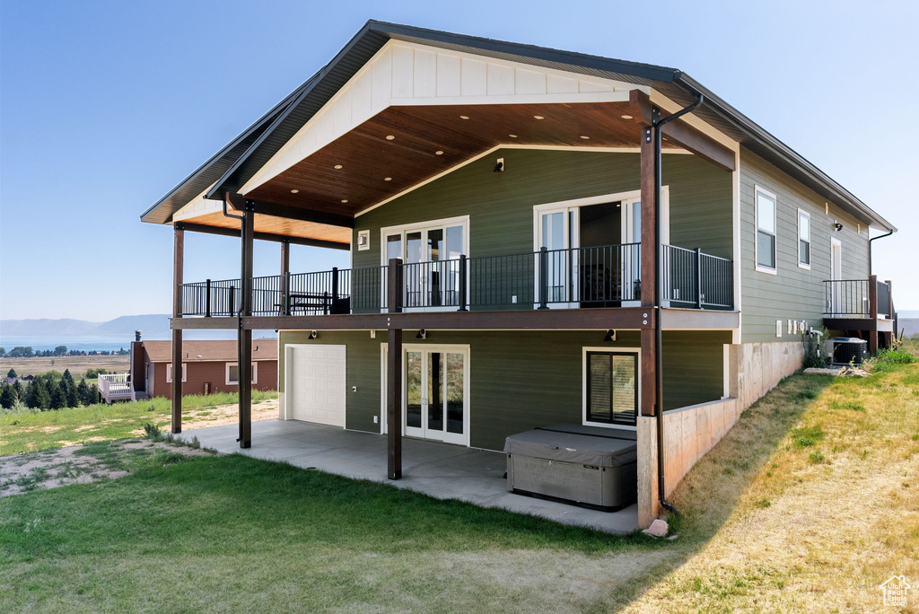 Rear view of property with central AC, a yard, a garage, french doors, and a patio area