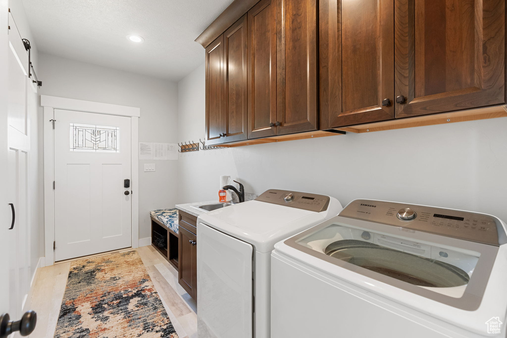 Washroom with sink, washer and dryer, cabinets, and light hardwood / wood-style floors