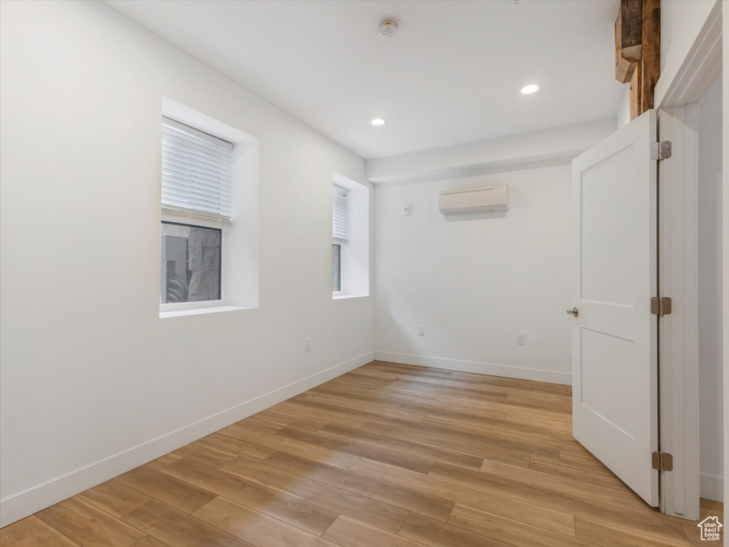 Unfurnished room featuring a wall mounted AC and light wood-type flooring