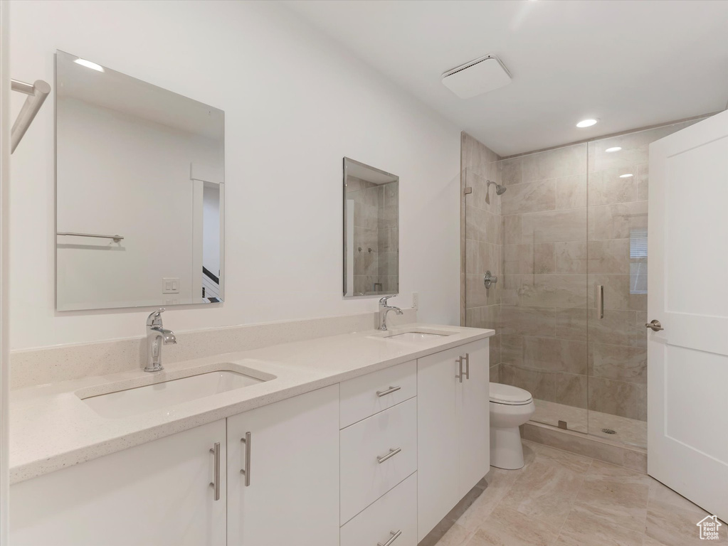 Bathroom featuring dual vanity, tile patterned floors, a shower with shower door, and toilet