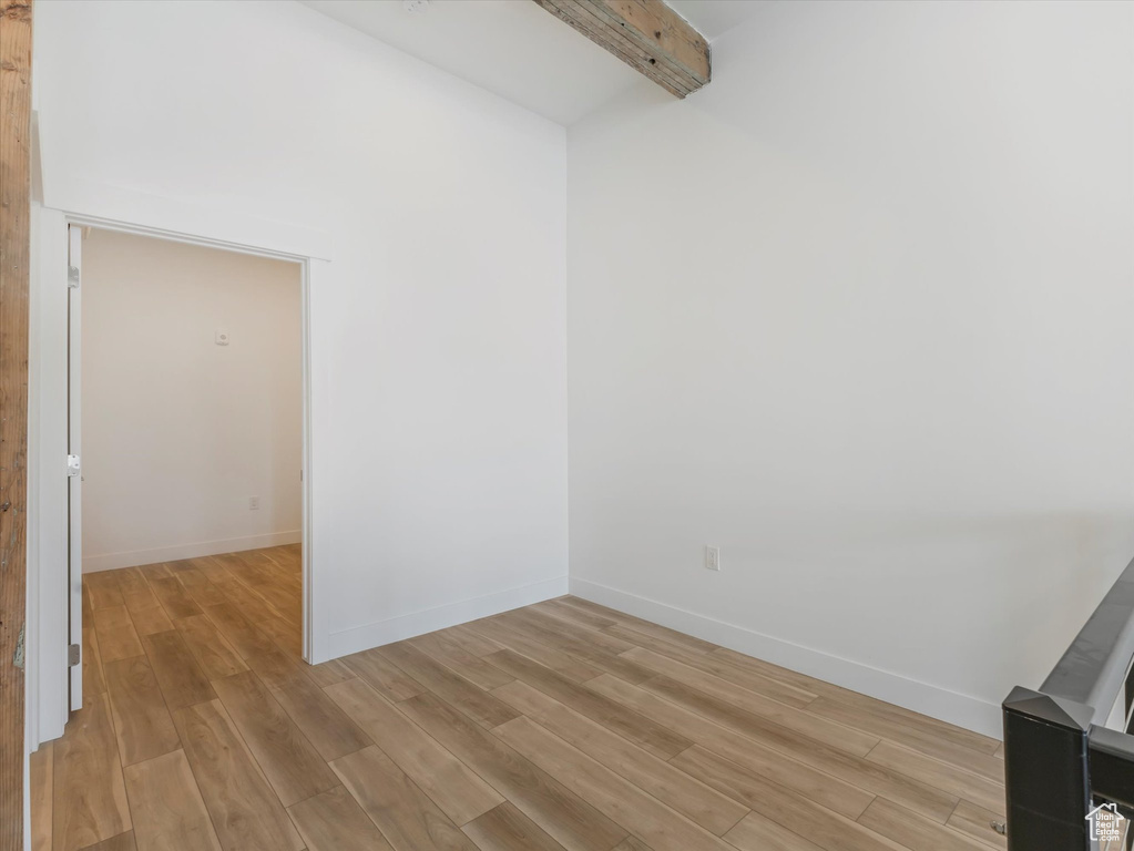 Unfurnished room featuring beam ceiling and wood-type flooring