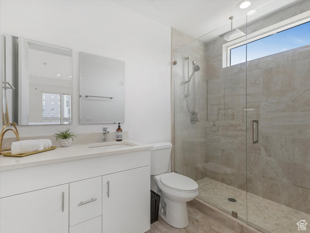 Bathroom with vanity, toilet, walk in shower, and tile patterned flooring