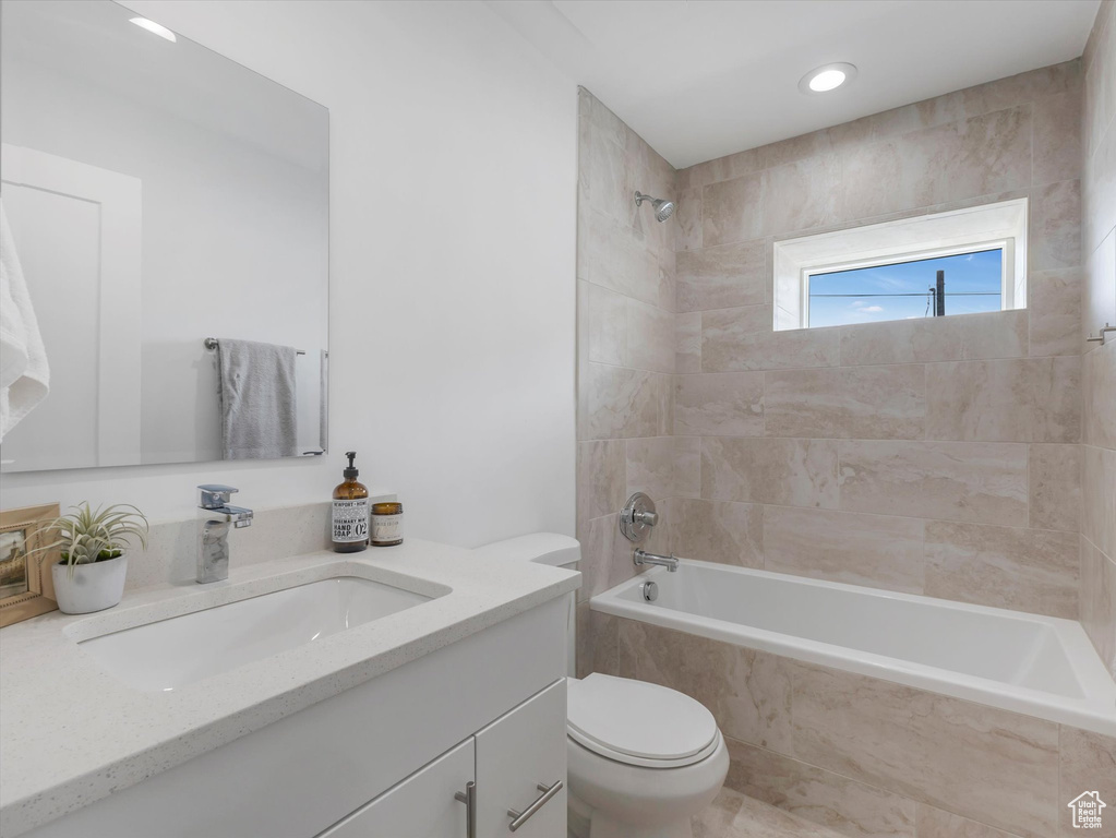 Full bathroom featuring tiled shower / bath combo, vanity, and toilet