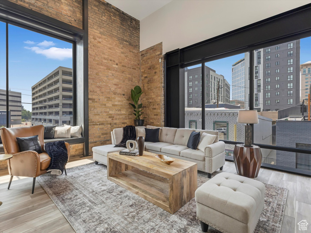 Living room with brick wall, plenty of natural light, and hardwood / wood-style floors