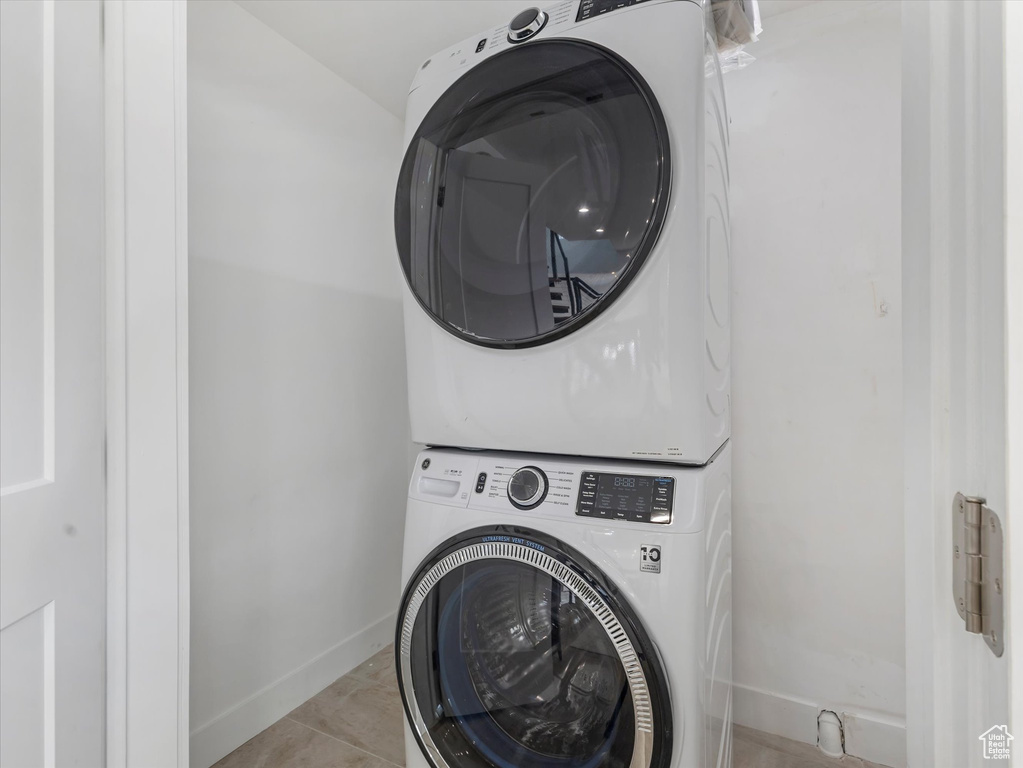 Clothes washing area with stacked washer / dryer and light tile patterned flooring