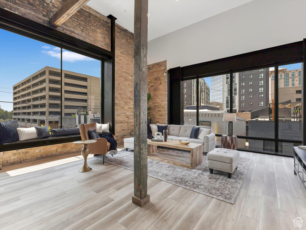 Living room with a high ceiling, brick wall, and light hardwood / wood-style floors