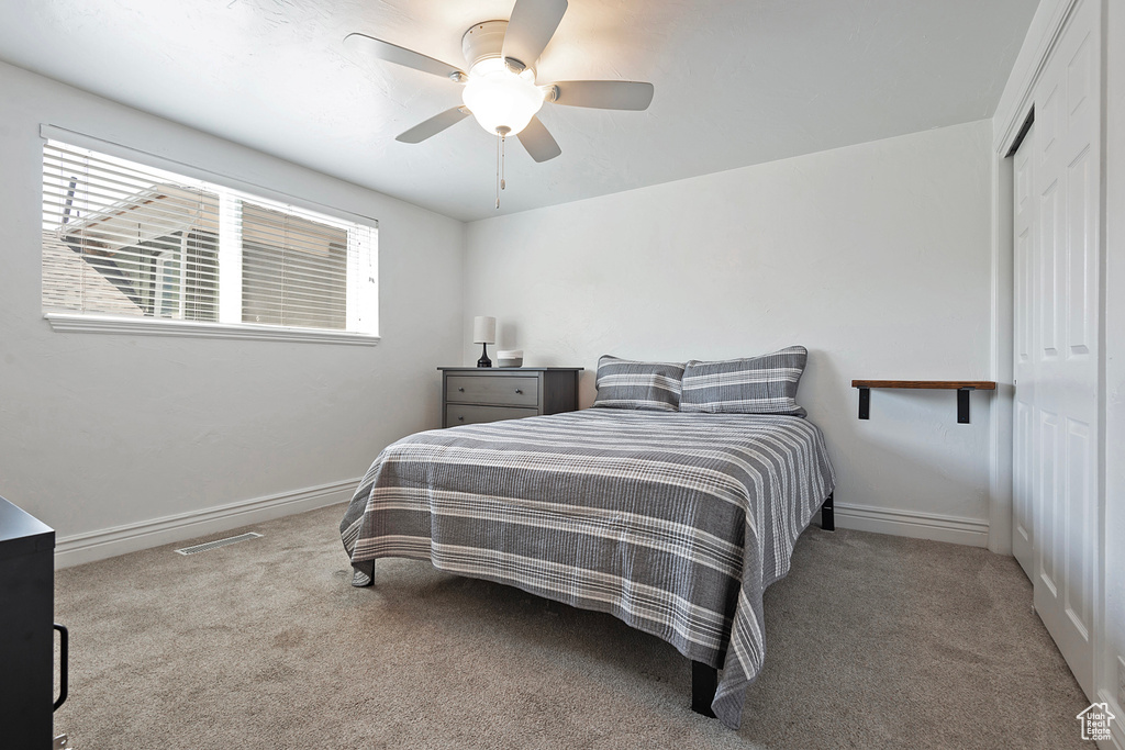 Bedroom with a closet, light colored carpet, and ceiling fan