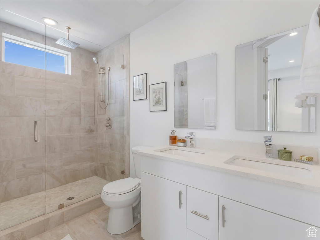 Bathroom featuring double vanity, walk in shower, tile patterned flooring, and toilet