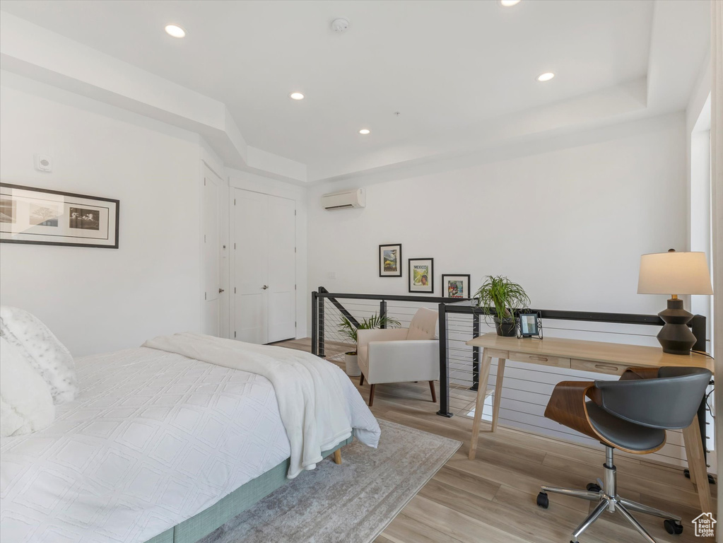 Bedroom with an AC wall unit and light wood-type flooring