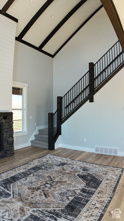 Staircase with beam ceiling, a fireplace, wood-type flooring, and high vaulted ceiling