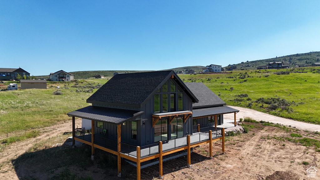 Rear view of house with a rural view and covered porch