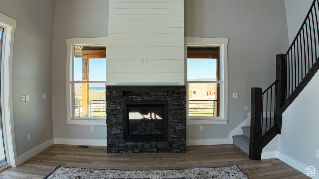 Living room featuring a stone fireplace, a high ceiling, and light hardwood / wood-style flooring