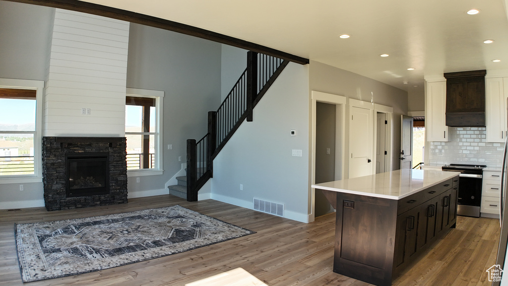 Kitchen with a fireplace, wood-type flooring, backsplash, and dark brown cabinetry