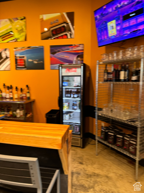 Bar featuring concrete floors, wine cooler, and wood counters