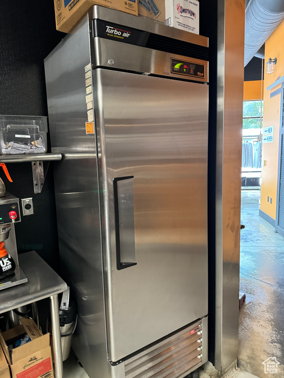 Room details featuring concrete floors and stainless steel refrigerator