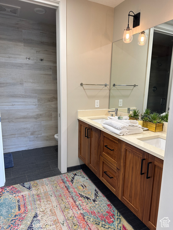 Bathroom with tile patterned floors, toilet, and double sink vanity