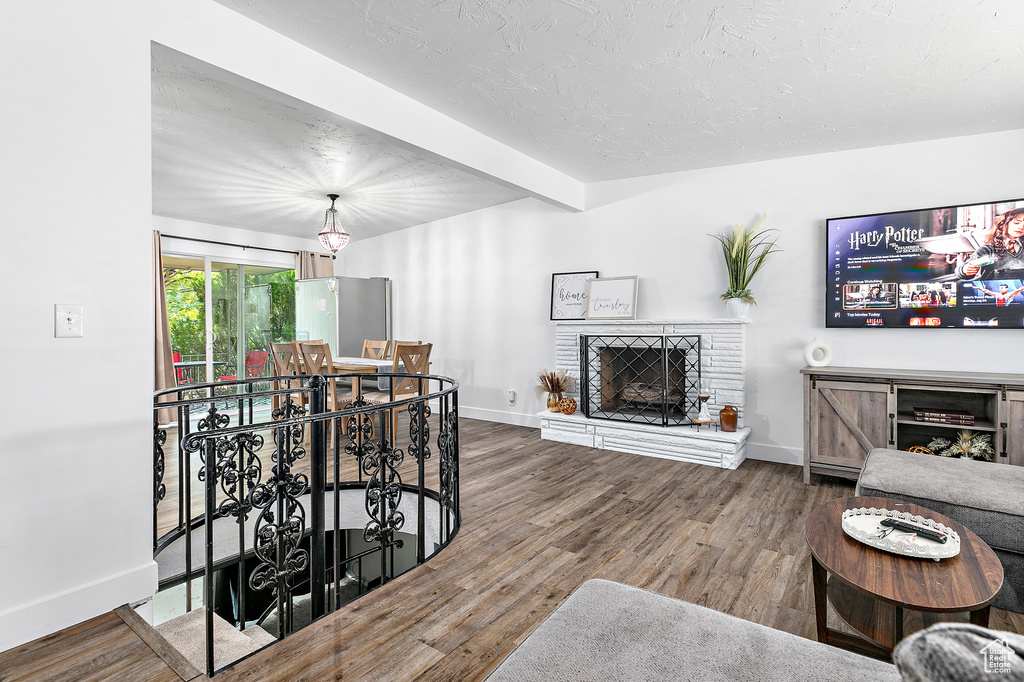 Living room with beam ceiling, a brick fireplace, and hardwood / wood-style flooring