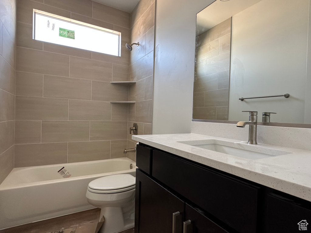 Full bathroom with vanity, toilet, hardwood / wood-style floors, and tiled shower / bath