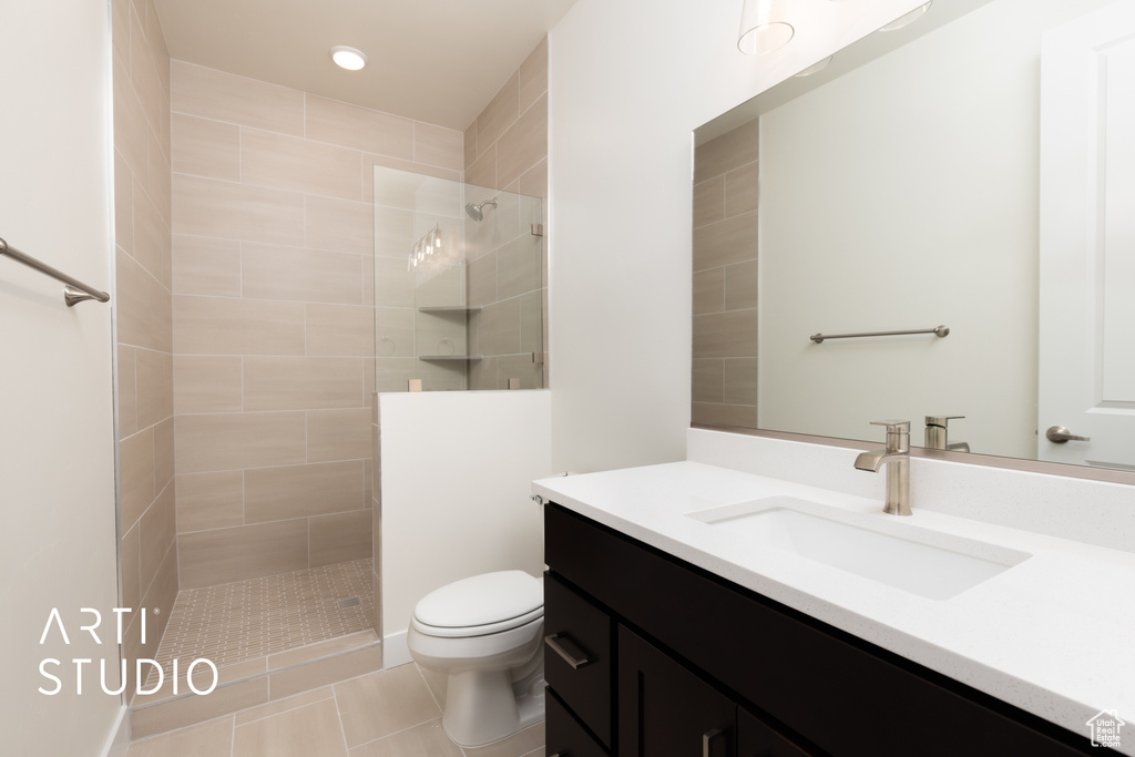 Bathroom with vanity, tiled shower, toilet, and tile patterned floors