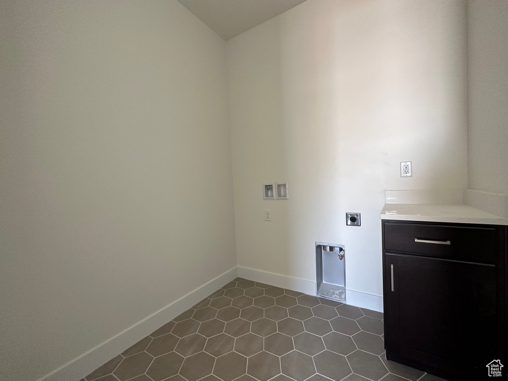 Washroom with hookup for a washing machine, hookup for an electric dryer, dark tile patterned floors, and cabinets