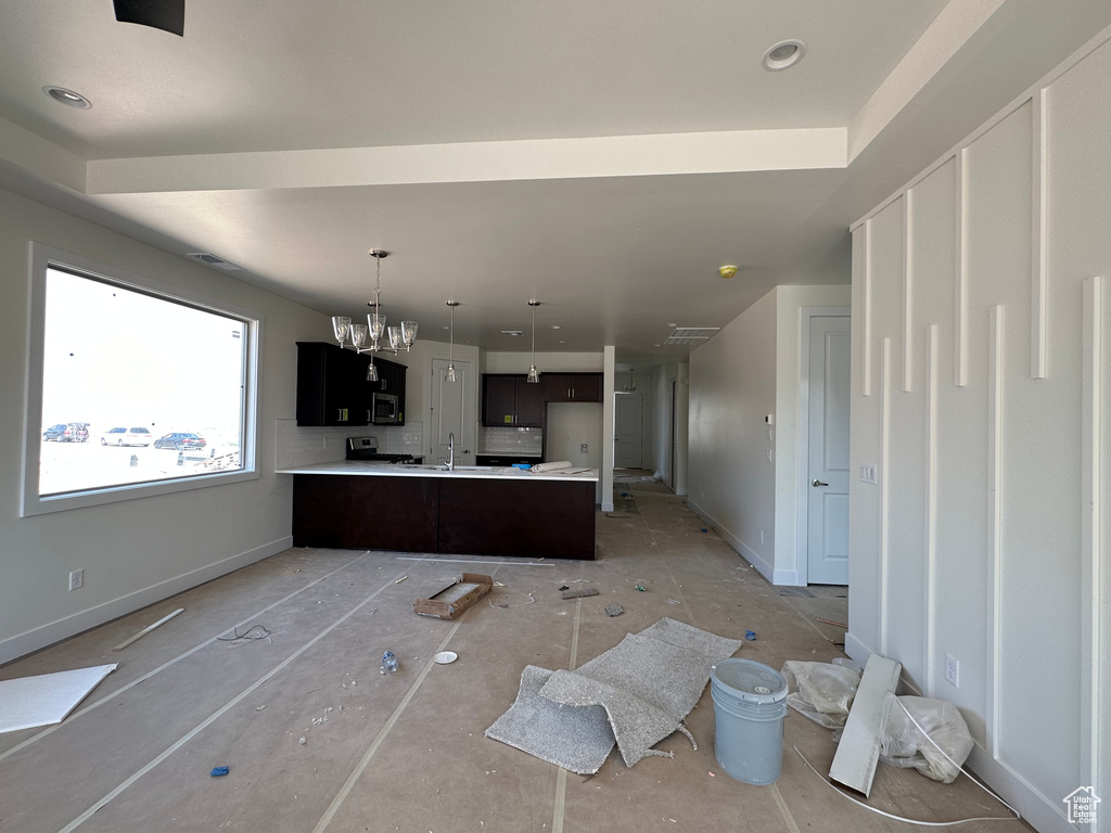 Kitchen featuring an inviting chandelier, kitchen peninsula, and sink