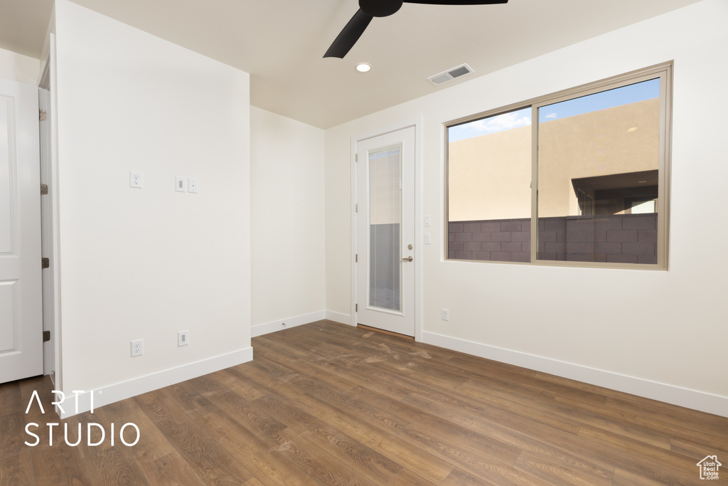 Empty room featuring dark wood-type flooring and ceiling fan